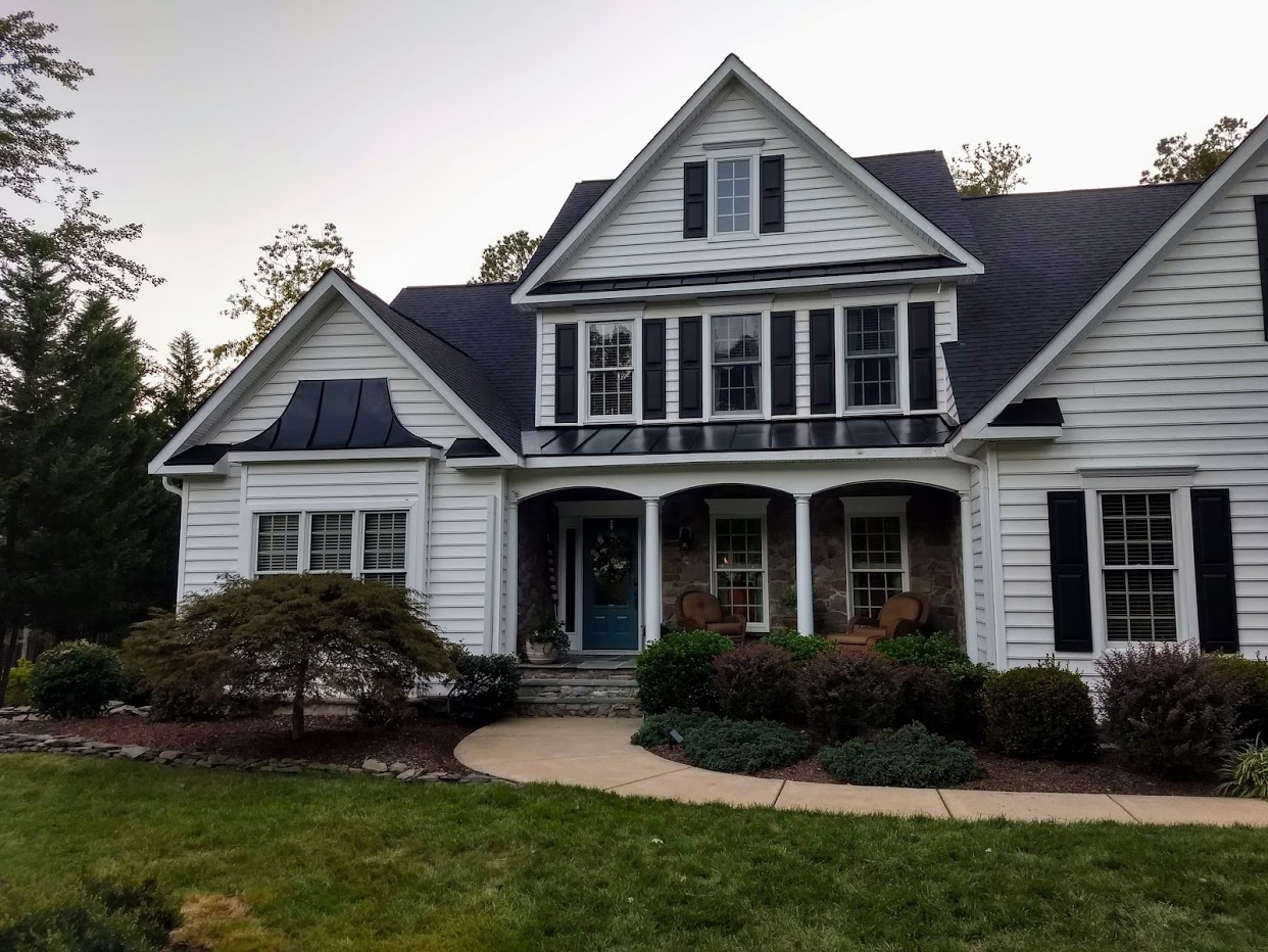 White-siding home with new architectural shingles and black standing-seam accent roofs