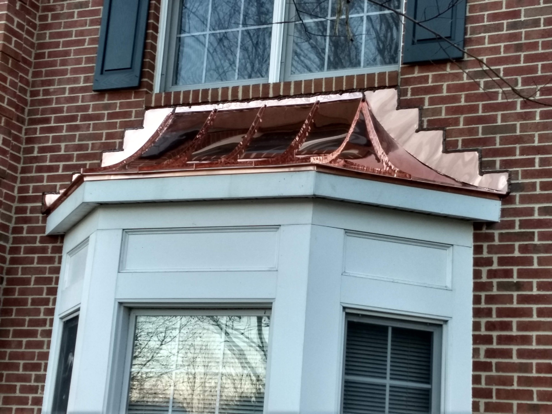 Copper bay-window roof detail on a brick home
