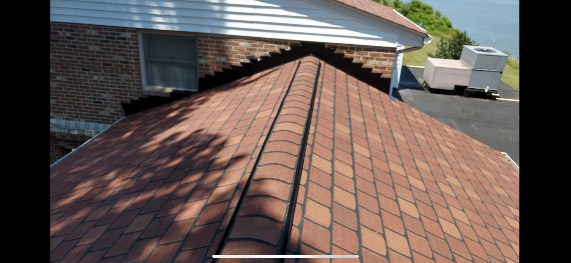 Red architectural shingles with black ridge vent along the roof peak