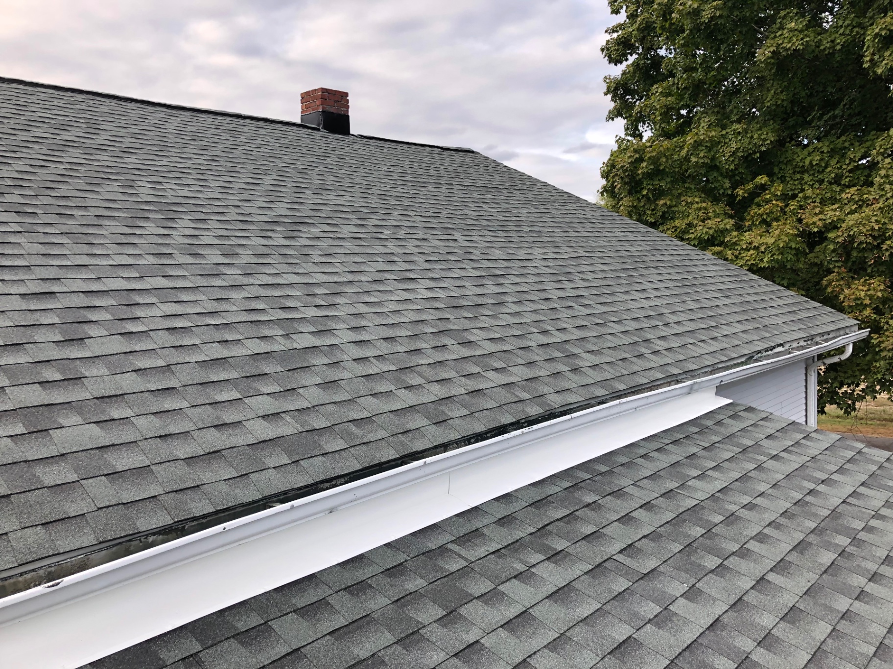 Wide view of a finished grey architectural shingle roof with new white drip edge