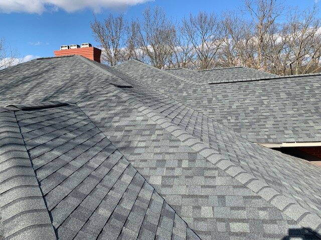 Close-up of new grey architectural shingles with ridge cap detail